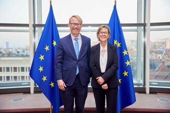 FIA president and CEO Walt Lukken standing next to Portuguese commissioner Maria Luis Albuquerque, who President von er Leyen has tasked her with overseeing the financial portfolio of the EU, with EU flags in the background.